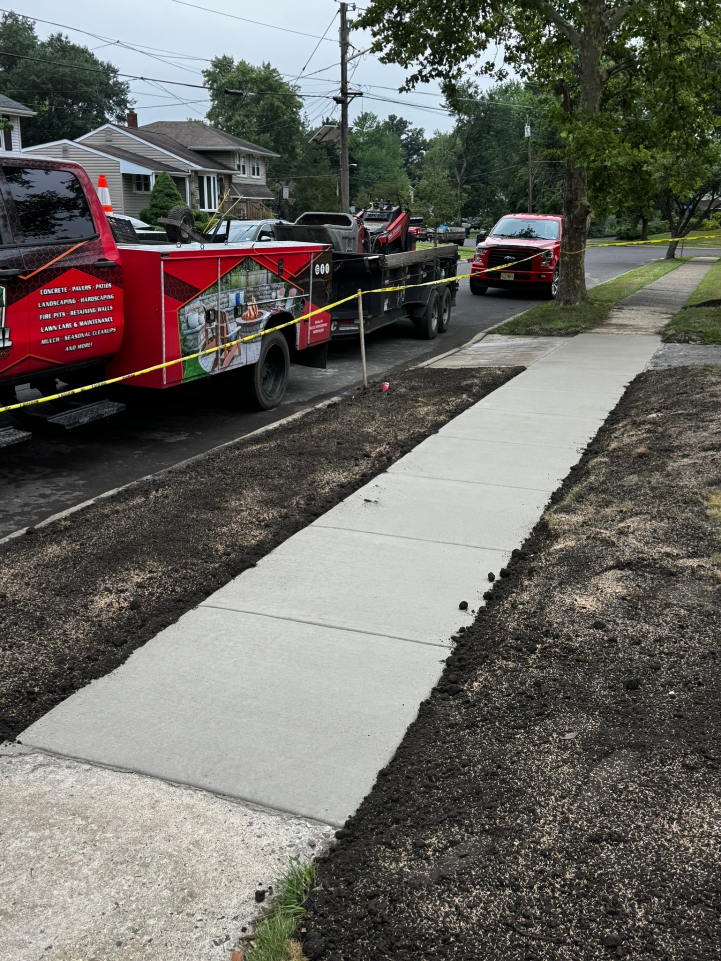 Newly poured concrete sidewalk next to red Universal Hardscaping truck in New Jersey