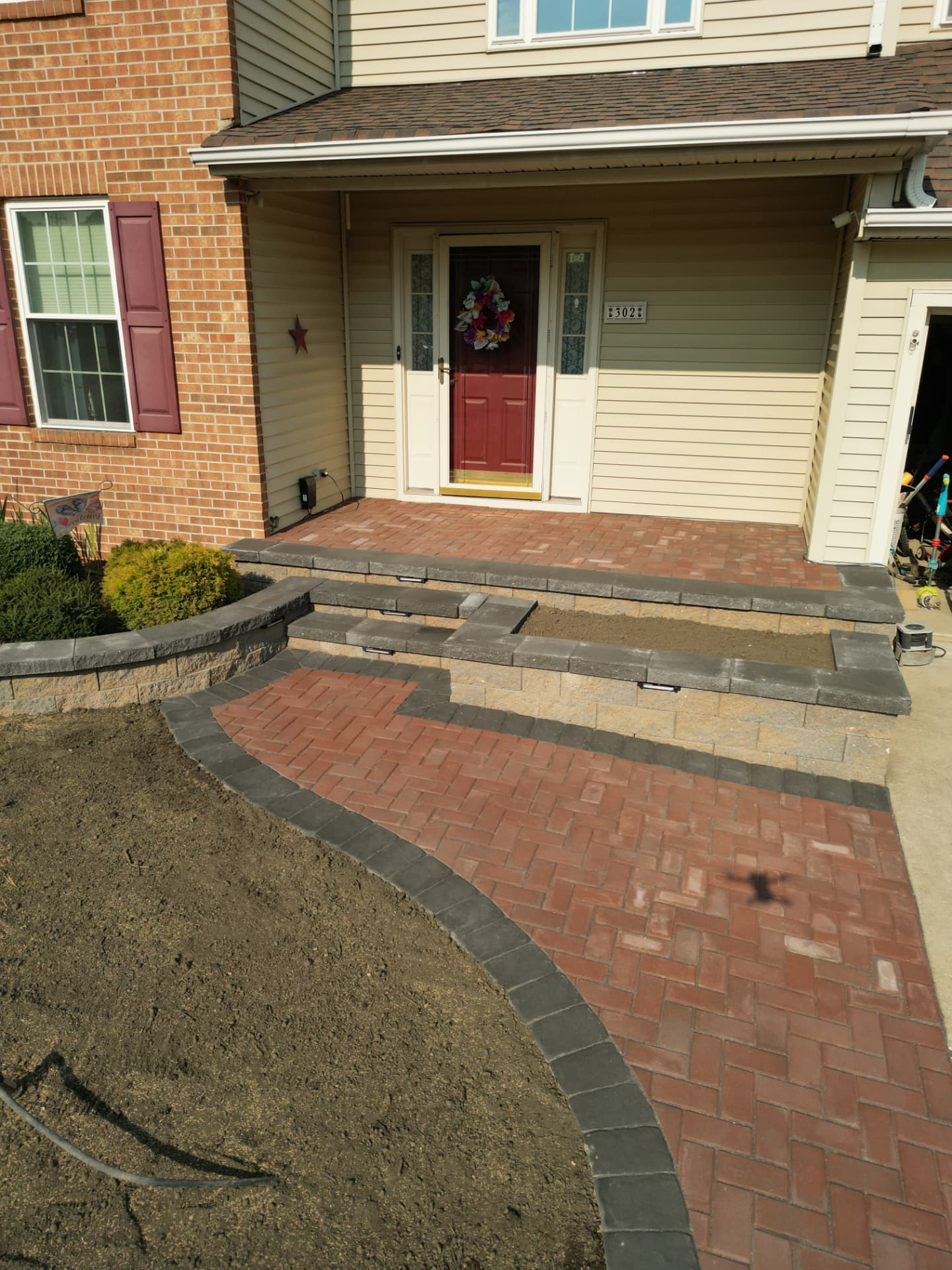 Overhead view of a brick paver front porch, charcoal-capped steps and curved herringbone walkway in New Jersey