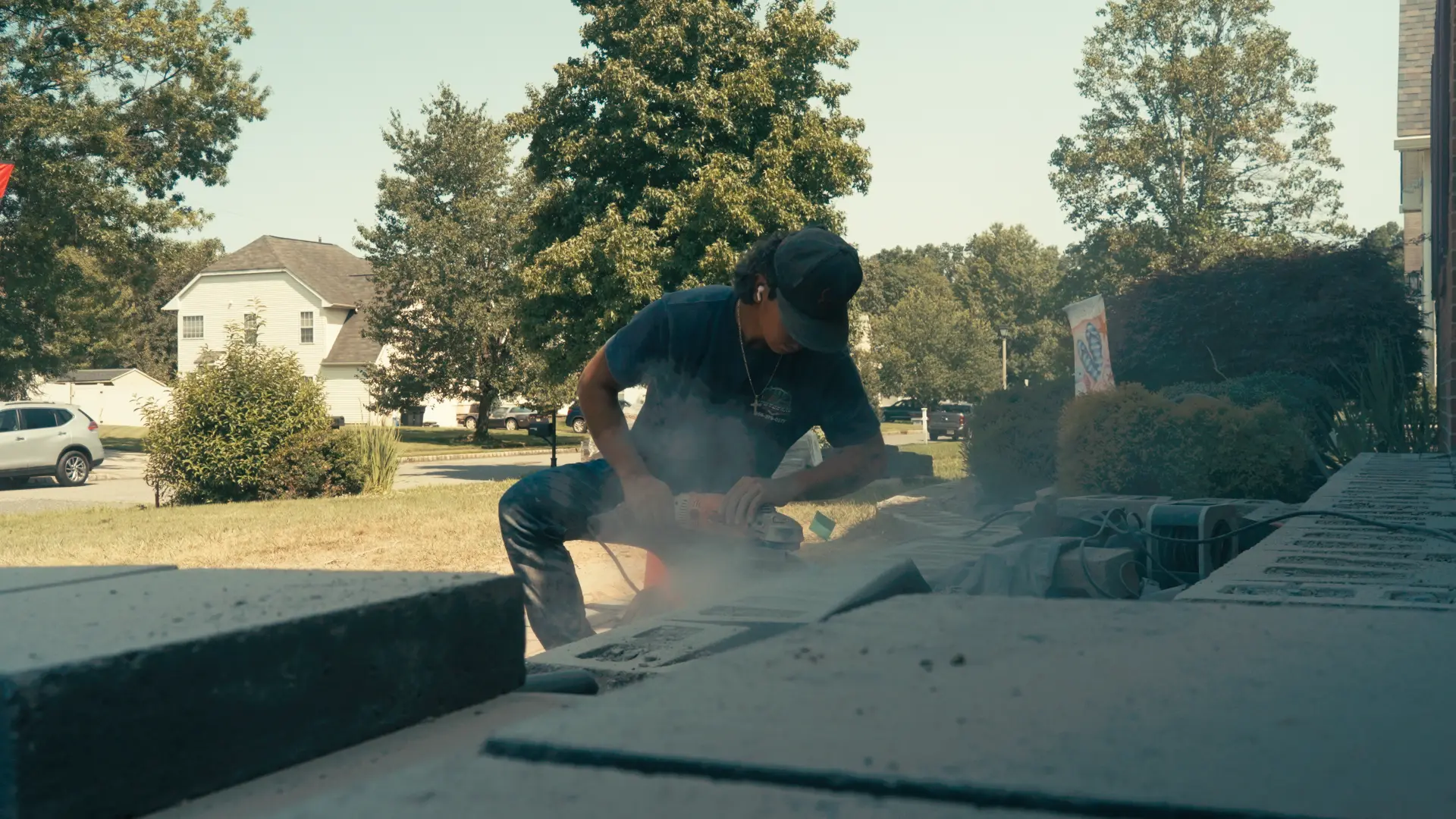 Crew member grinding wall caps on a front yard hardscape build