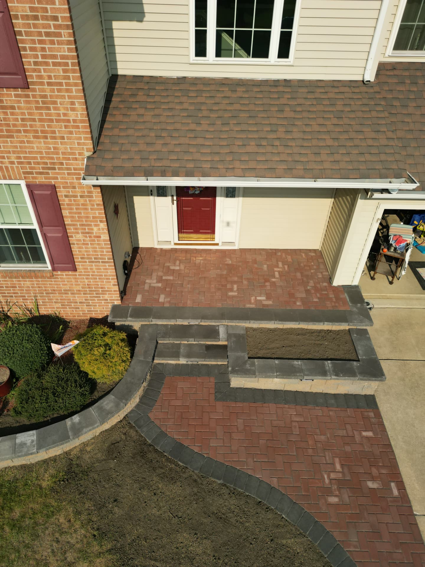 Top-down aerial of a brick paver porch, steps and herringbone walkway wrapping to the driveway in New Jersey
