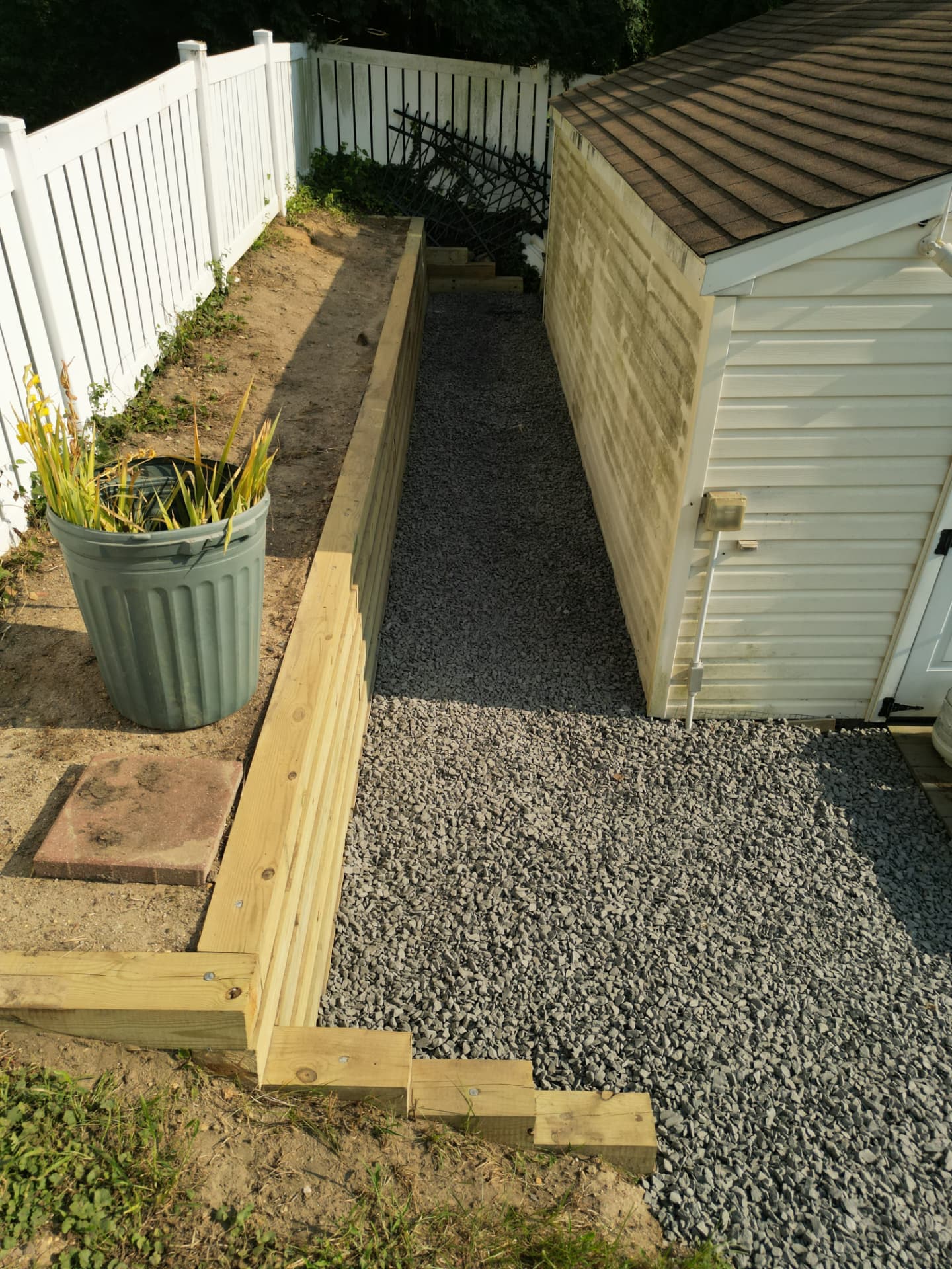 Crushed stone shed pad and pathway with pressure-treated timber retaining wall in a New Jersey backyard