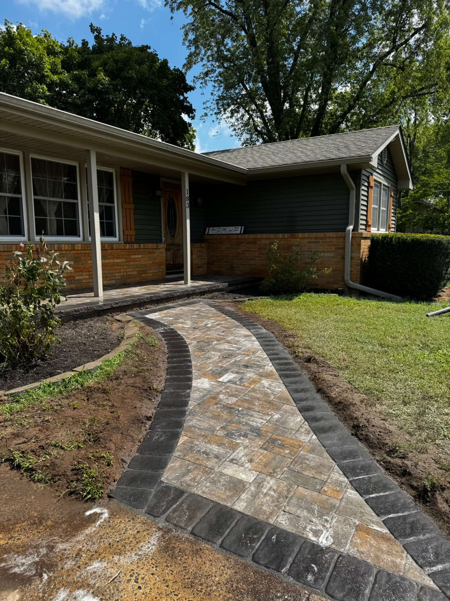 Curved multi-tone paver front walkway with charcoal cobble border leading to a covered porch in New Jersey